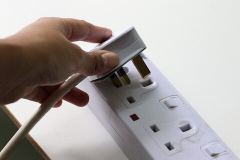 woman inserting plug in electrical socket